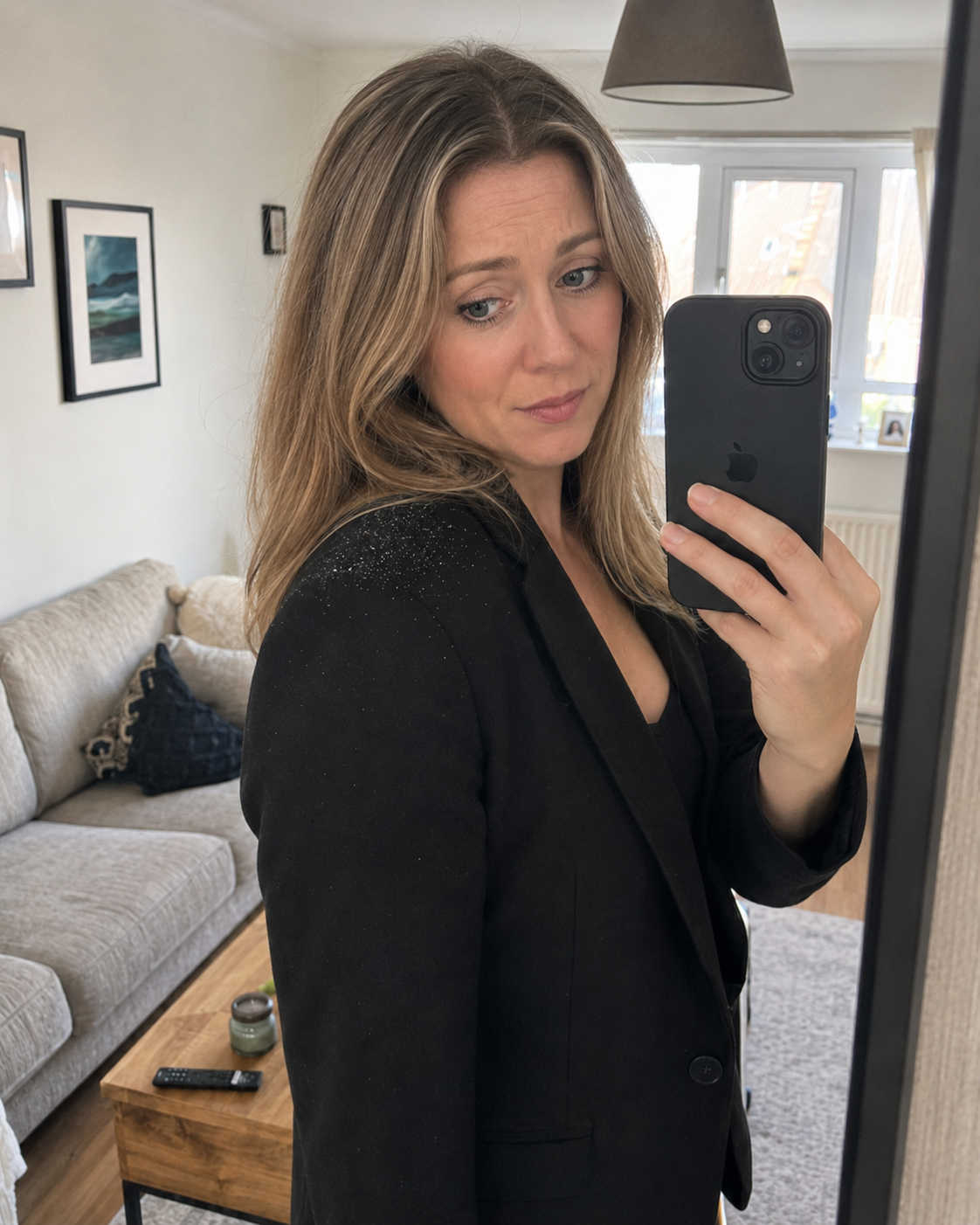 Woman in a black blazer showing visible scalp flakes on her shoulder